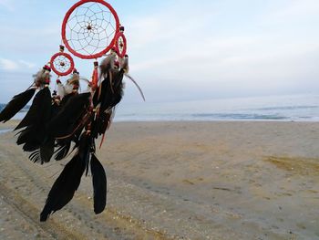 Dreamcatcher hanging at beach against sky