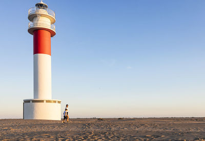 Mother and son walking near a beautiful lighthouse