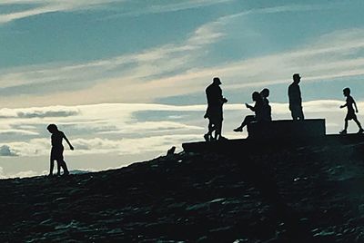 Men walking on silhouette people against sky