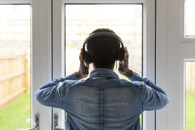 Woman with headphones looking through window