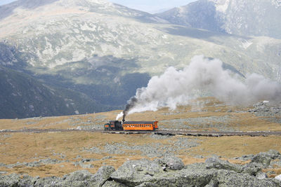 Steam train of mount washington cog railway pusing up coach to the summit at good weather conditions