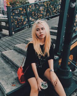 Portrait of woman sitting by railing