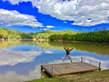 Rear view of man on boat in lake against sky