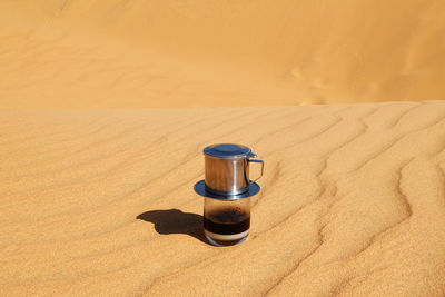 Drip black coffee in vietnamese style with condensed milk on a red sand. 