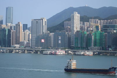 Boats in sea against modern buildings in city