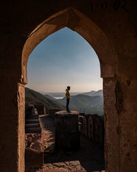 Man standing on arch against sky