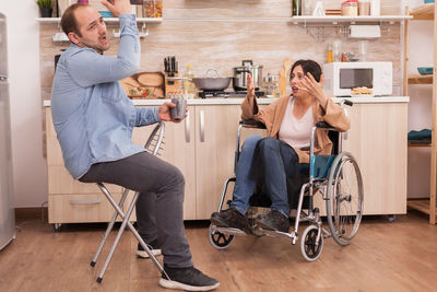 Disabled woman arguing with man in kitchen at home