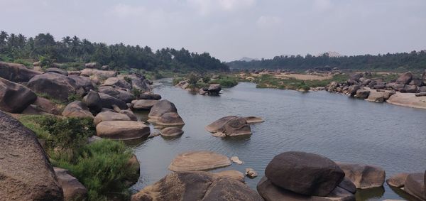 Rocks by river against sky
