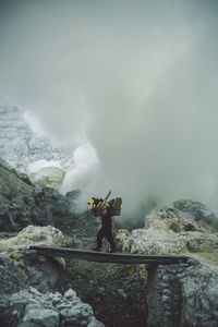 Man standing on rock against mountains during winter