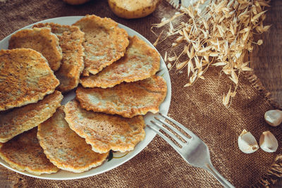 Potato pancakes on a plate and fork on a linen background