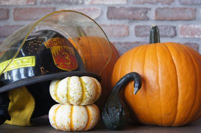 Close-up of pumpkins and helmet on table at home