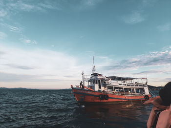 Person on ship in sea against sky