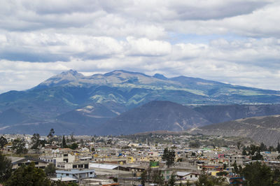Aerial view of cityscape and mountains against sky
