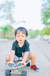 Cute boy sitting on skateboard