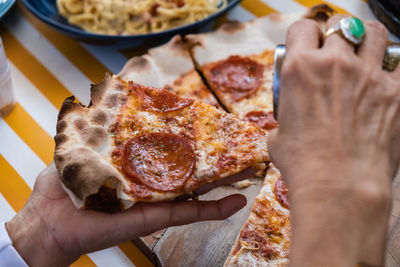 Close-up of hand holding pizza