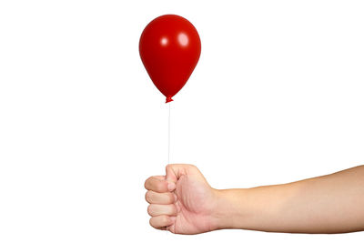 Midsection of person holding balloons against white background