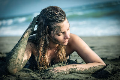 Beautiful sensuous woman lying on sand at beach