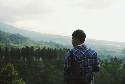 Rear view of man standing against mountains and sky