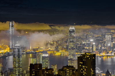 Illuminated buildings in city against sky at night