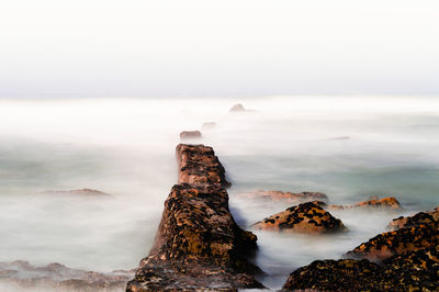 Rock formations on shore against sky