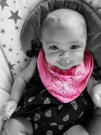 Portrait of cute baby girl sitting on bed at home