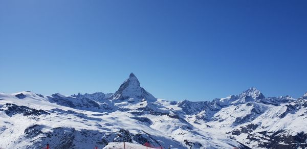 Scenic view of snowcapped mountains against clear blue sky