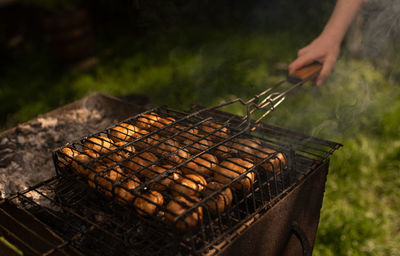 Cropped hand of man preparing food on barbecue grill