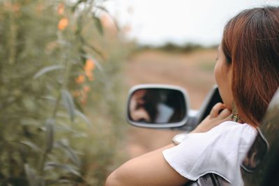 Rear view of woman looking through car window