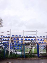 Empty chairs on field against sky