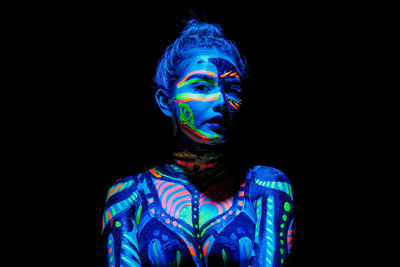 Portrait of man wearing multi colored light painting against black background