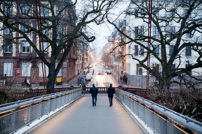 Rear view of people walking on bridge in winter