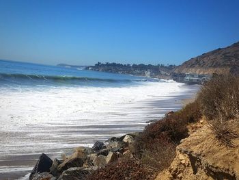 Scenic view of beach against clear blue sky