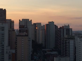 Modern buildings in city against sky during sunset