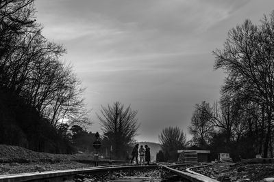 Railroad tracks amidst bare trees against sky