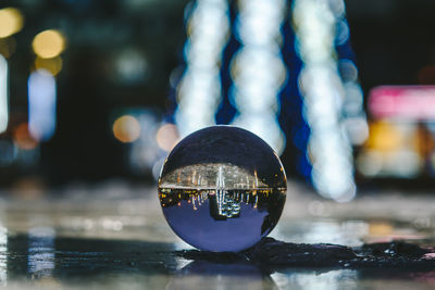 Close-up of crystal ball with reflection against defocused lights at night
