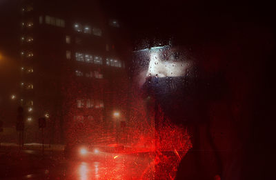 Illuminated city street seen through wet window