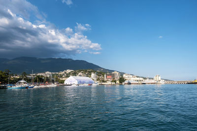 Sea by city buildings against sky