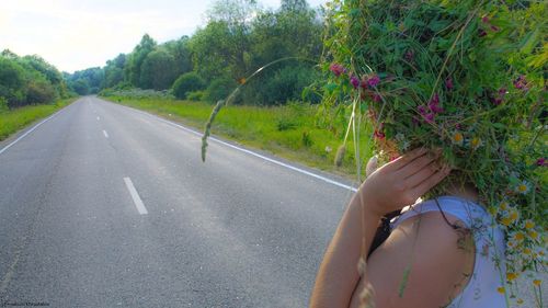 Close-up of hand on road against trees