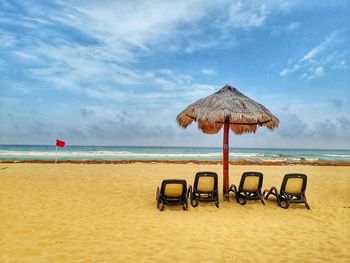 Deck chairs on beach against sky