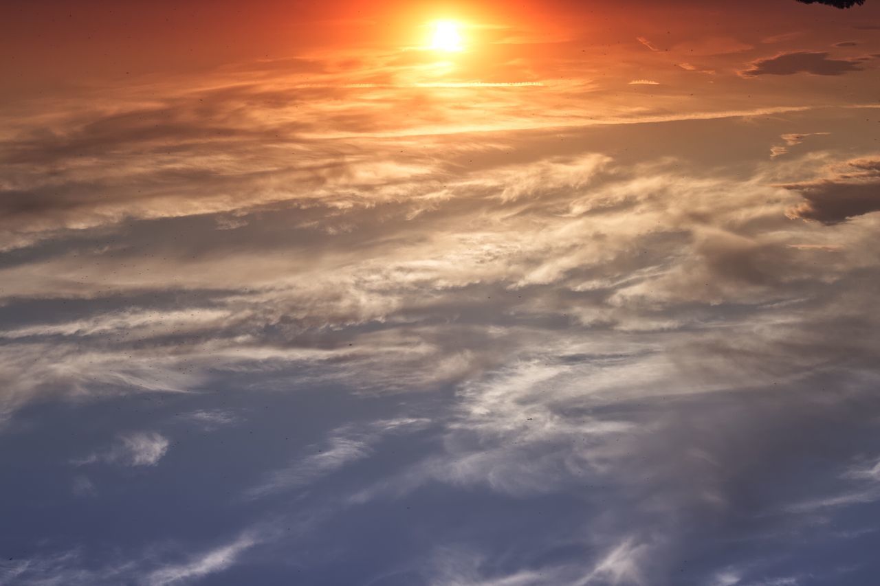 LOW ANGLE VIEW OF SUN STREAMING THROUGH CLOUDS