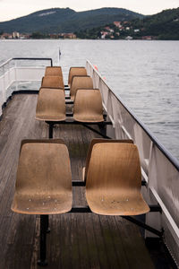 Empty chairs on pier at lake