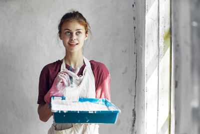 Portrait of young woman standing against wall