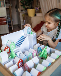 Origami advent calendar, paper craft. girl looking upon paper houses with number and paper tree