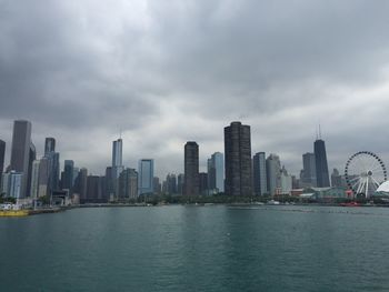 Sea by modern buildings against sky in city