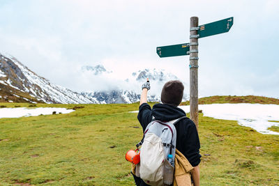 Rear view of man photographing on mountain against sky