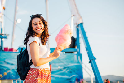 Portrait of smiling young woman standing against sky