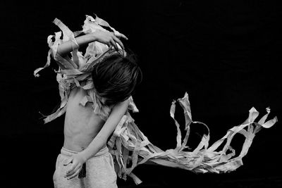 Shirtless boy dancing against black background