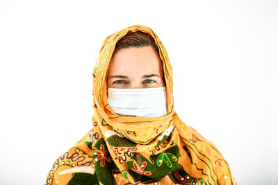 Portrait of woman wearing mask standing against white background