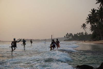 Silhouette people on beach against clear sky