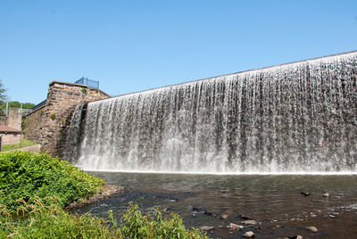 Water splashing on dam against sky